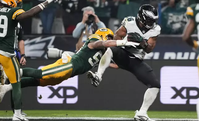 Philadelphia Eagles running back Saquon Barkley (26) scores past Green Bay Packers linebacker Isaiah McDuffie (58) during the first half of an NFL football game, Friday, Sept. 6, 2024, at the Neo Quimica Arena in Sao Paulo. (AP Photo/Doug Benc)