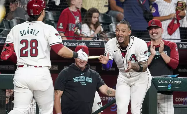 Arizona Diamondbacks' Ketel Marte, right, and manager Torey Lovullo, far right, greets Eugenio Suárez after Suárez's home run against the San Diego Padres during the seventh inning of a baseball game, Sunday, Sept. 29, 2024, in Phoenix. (AP Photo/Darryl Webb)