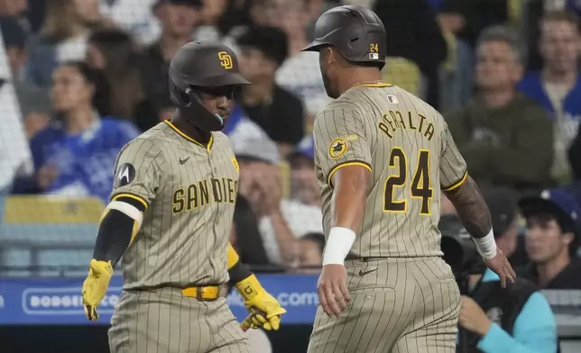 San Diego Padres' David Peralta, right, celebrates with teammate Jurickson Profar after scoring off an RBI ground out by Luis Arraez during the fifth inning of a baseball game against the Los Angeles Dodgers Thursday, Sept. 26, 2024, in Los Angeles. (AP Photo/Ashley Landis)