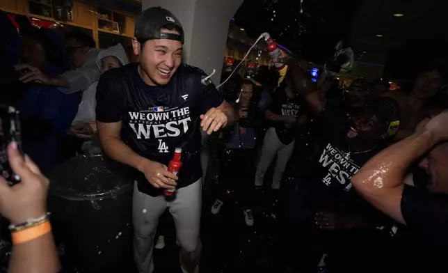 Los Angeles Dodgers designated hitter Shohei Ohtani celebrates with teammates after the Dodgers defeated the San Diego Padres 7-2 in a baseball game to clinch the National League West division Thursday, Sept. 26, 2024, in Los Angeles. (AP Photo/Ashley Landis)