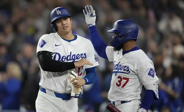 Los Angeles Dodgers' Shohei Ohtani, left, celebrates with teammate Teoscar Hernandez after hitting an RBI single and advancing to second off a throwing error by San Diego Padres right fielder Fernando Tatis Jr. during the seventh inning of a baseball game Thursday, Sept. 26, 2024, in Los Angeles. (AP Photo/Ashley Landis)