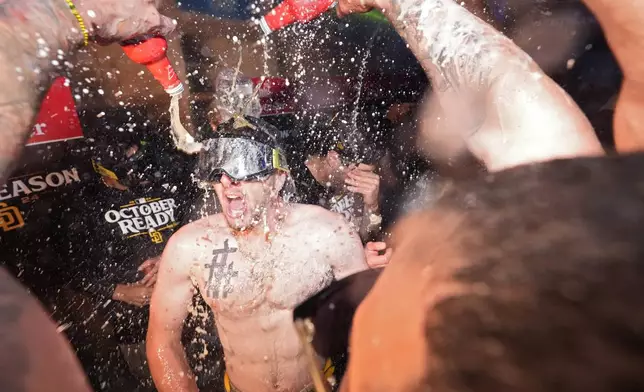 San Diego Padres' Jackson Merrill, center, celebrates with teammates after the Padres clinched a playoff spot with a triple play to end their baseball game against the Los Angeles Dodgers, Tuesday, Sept. 24, 2024, in Los Angeles. (AP Photo/Mark J. Terrill)