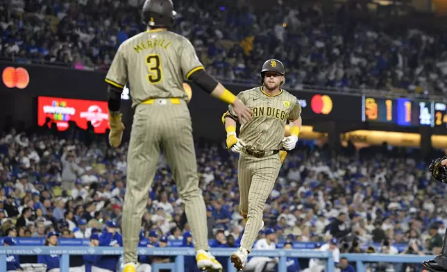 San Diego Padres' Jake Cronenworth, right, scores after hitting a two-run home run as Jackson Merrill waits to congratulate him during the second inning of a baseball game against the Los Angeles Dodgers, Tuesday, Sept. 24, 2024, in Los Angeles. (AP Photo/Mark J. Terrill)