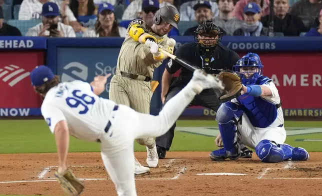 San Diego Padres' Jake Cronenworth, second from left, hits a two-run home run as Los Angeles Dodgers starting pitcher Landon Knack, left, washes along with catcher Will Smith, right, and home plate umpire Tripp Gibson during the second inning of a baseball game, Tuesday, Sept. 24, 2024, in Los Angeles. (AP Photo/Mark J. Terrill)