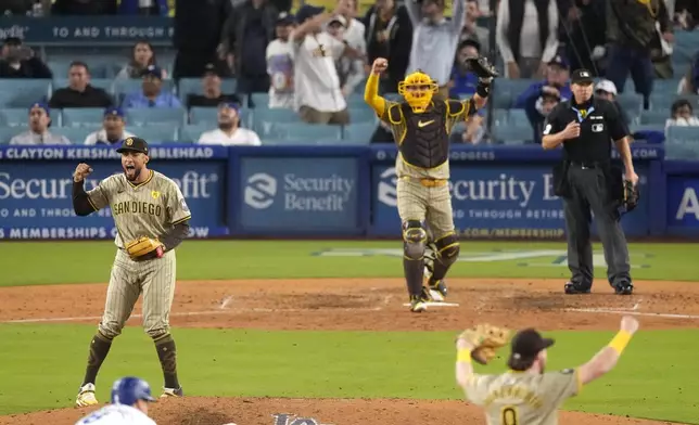 San Diego Padres relief pitcher Robert Suarez, left, celebrates along with catcher Kyle Higashioka, center, and Jake Cronenworth, right, as Los Angeles Dodgers' Kiké Hernández stands on second base after the Padres clinched a playoff spot with a triple play to end their baseball game against the Los Angeles Dodgers, Tuesday, Sept. 24, 2024, in Los Angeles. (AP Photo/Mark J. Terrill)