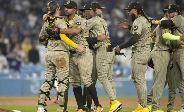 Members of the San Diego Padres celebrate after the Padres clinched a playoff spot with a triple play to end their baseball game as Los Angeles Dodgers' Shohei Ohtani stands at the plate, Tuesday, Sept. 24, 2024, in Los Angeles. (AP Photo/Mark J. Terrill)