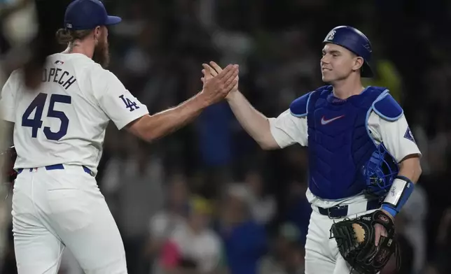 Los Angeles Dodgers relief pitcher Michael Kopech, left, celebrates with teammate catcher Will Smith after the Dodgers defeated the San Diego Padres 7-2 in a baseball game to clinch the National League West division Thursday, Sept. 26, 2024, in Los Angeles. (AP Photo/Ashley Landis)