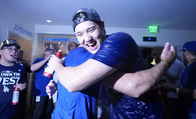 Los Angeles Dodgers designated hitter Shohei Ohtani hugs a teammate after the Dodgers defeated the San Diego Padres 7-2 in a baseball game to clinch the National League West division Thursday, Sept. 26, 2024, in Los Angeles. (AP Photo/Ashley Landis)