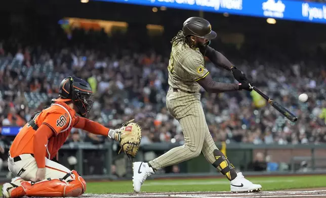 San Diego Padres' Fernando Tatis Jr., right, hits a two-run home run in front of San Francisco Giants catcher Patrick Bailey during the first inning of a baseball game in San Francisco, Friday, Sept. 13, 2024. (AP Photo/Jeff Chiu)