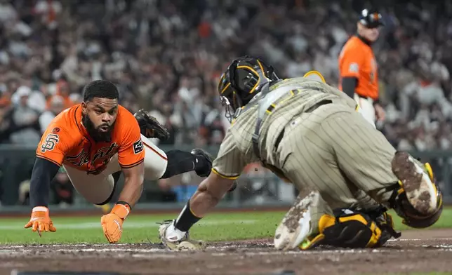 San Diego Padres catcher Elias Díaz, right, waits to tag out San Francisco Giants' Heliot Ramos at home during the sixth inning of a baseball game in San Francisco, Friday, Sept. 13, 2024. (AP Photo/Jeff Chiu)