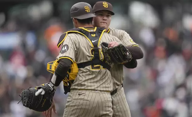 San Diego Padres catcher Kyle Higashioka, left, celebrates with pitcher Adrian Morejon, right, after they defeated the San Francisco Giants in 10 innings of a baseball game in San Francisco, Sunday, Sept. 15, 2024. (AP Photo/Jeff Chiu)