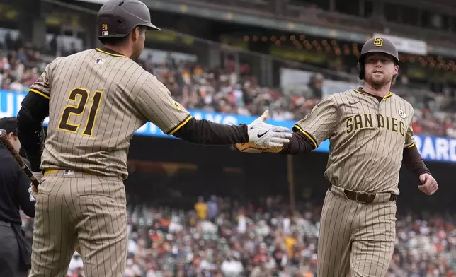 San Diego Padres' Jake Cronenworth, right, is congratulated by Kyle Higashioka, wearing the number 21 on his jersey in honor of Roberto Clemente, after scoring during the tenth inning of a baseball game against the San Francisco Giants in San Francisco, Sunday, Sept. 15, 2024. (AP Photo/Jeff Chiu)