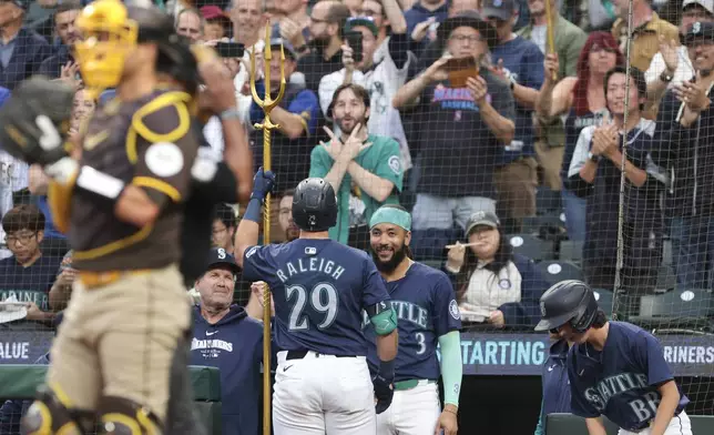 Seattle Mariners' Cal Raleigh (29) celebrates with manager Dan Wilson, center left, and J.P. Crawford (3) after hitting a solo home run off San Diego Padres starting pitcher Yu Darvish during the first inning of a baseball game, Tuesday, Sept. 10, 2024, in Seattle. (AP Photo/Jason Redmond)