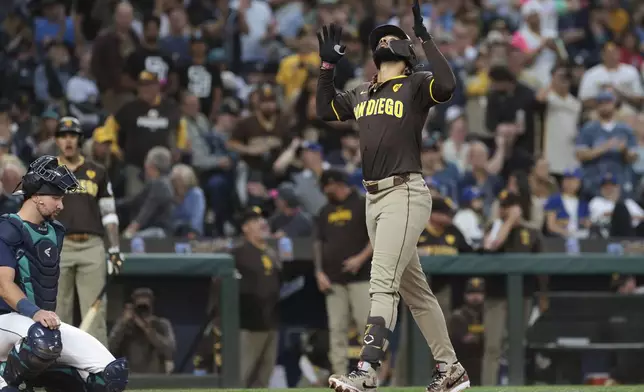 San Diego Padres' Fernando Tatis Jr. celebrates at home after hitting a three-run home run as Seattle Mariners catcher Cal Raleigh, left, looks on during the third inning of a baseball game, Tuesday, Sept. 10, 2024, in Seattle. (AP Photo/Jason Redmond)