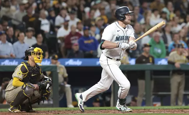 Seattle Mariners' Luke Raley follows through on a two-RBI single as San Diego Padres catcher Kyle Higashioka, left, looks on during the third inning of a baseball game, Wednesday, Sept. 11, 2024, in Seattle. (AP Photo/Jason Redmond)