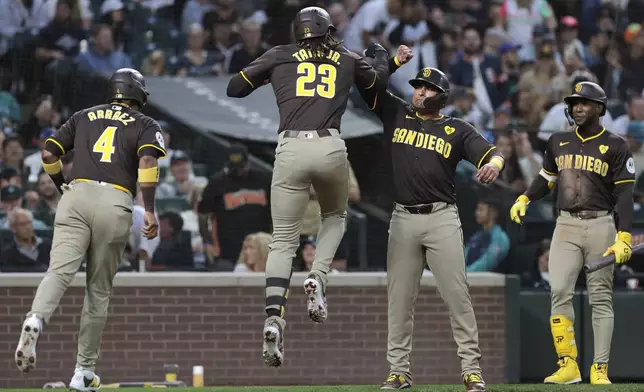 San Diego Padres' Fernando Tatis Jr. (23) celebrates with, from left, designated hitter Luis Arraez (4) Donovan Solano and Jurickson Profar after hitting a three-run home run the third inning of a baseball game against the Seattle Mariners, Tuesday, Sept. 10, 2024, in Seattle. (AP Photo/Jason Redmond)