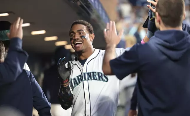 Seattle Mariners' Julio Rodríguez celebrates in the dugout after scoring on a two-RBI single by Luke Raley during the third inning of a baseball game against the San Diego Padres, Wednesday, Sept. 11, 2024, in Seattle. (AP Photo/Jason Redmond)