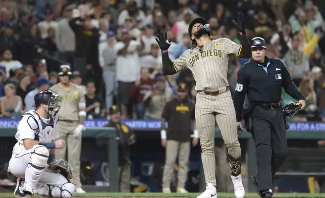 San Diego Padres' Fernando Tatis Jr., right, celebrates at home after hitting a home run off Seattle Mariners starting pitcher Bryan Woo as catcher Cal Raleigh, left, looks on during the seventh inning of a baseball game, Wednesday, Sept. 11, 2024, in Seattle. (AP Photo/Jason Redmond)