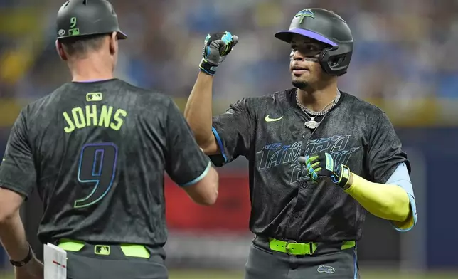 Tampa Bay Rays' Christopher Morel celebrates his RBI single off San Diego Padres starting pitcher Randy Vasquez with first base coach Michael Johns (9) during the fifth inning of a baseball game Saturday, Aug. 31, 2024, in St. Petersburg, Fla. (AP Photo/Chris O'Meara)