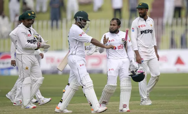 Bangladesh's Mushfiqur Rahim, second right, talks with Shakib Al Hasan, center, as they walk off the field after winning the second test cricket match against Pakistan, in Rawalpindi, Pakistan, Tuesday, Sept. 3, 2024. (AP Photo/Anjum Naveed)