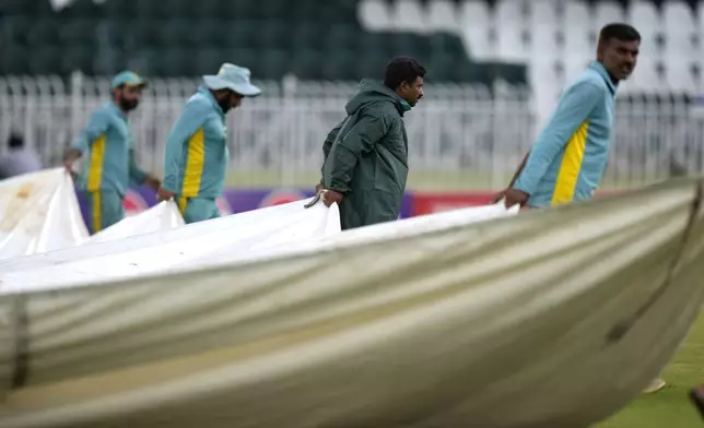 Ground staff pull the sheet to cover the ground after game stop due to bad light during the fourth day of second test cricket match between Pakistan and Bangladesh, in Rawalpindi, Pakistan, Monday, Sept. 2, 2024. (AP Photo/Anjum Naveed)