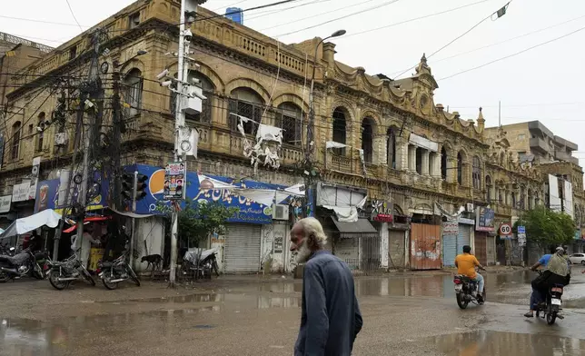 A man walks past an old building in downtown Karachi, Pakistan, Wednesday, Aug. 28, 2024. (AP Photo/Fareed Khan)