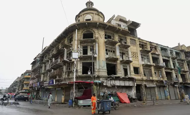 People walk past an old building in downtown Karachi, Pakistan, Thursday, Aug. 29, 2024. (AP Photo/Fareed Khan)