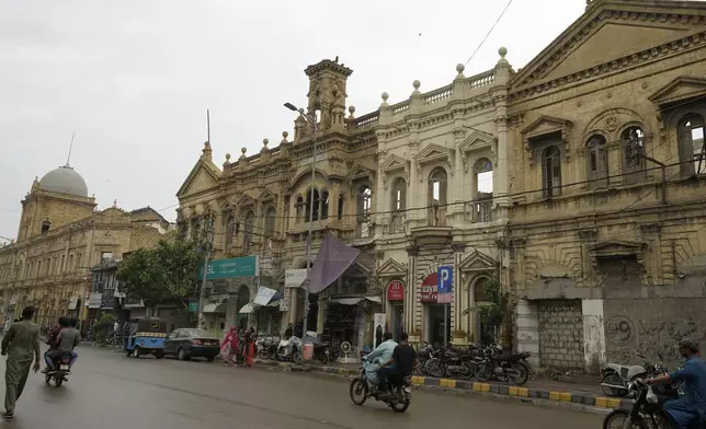 Motorcyclists drive on a road with old buildings in downtown Karachi, Pakistan, Thursday, Aug. 29, 2024. (AP Photo/Fareed Khan)