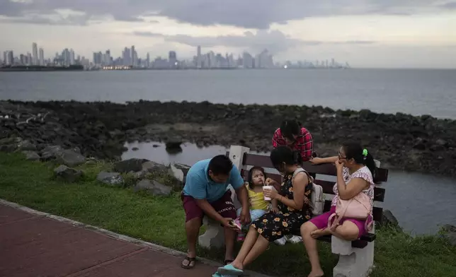 A family relaxes in Amador Causeway during sunset in Panama City, Sunday, Sept. 15, 2024. (AP Photo/Matias Delacroix)