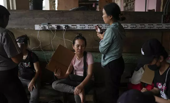 Migrants from Vietnam charge their phones at a camp for those who walk across the Darien Gap in hope of reaching the U.S., in Lajas Blancas, Panama, Thursday, Sept. 26, 2024. (AP Photo/Matias Delacroix)