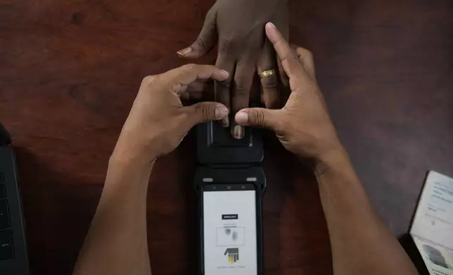 A Panamanian immigration officer takes the fingerprints of William Kanana, from the Democratic Republic of the Congo, at a post in Lajas Blancas, Panama, where migrants who trekked across the Darién Gap are processed, Thursday, Sept. 26, 2024. (AP Photo/Matias Delacroix)