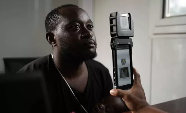 A Panamanian immigration officer does a biometric check on William Kanana, from the Democratic Republic of the Congo, at a post in Lajas Blancas, Panama, where migrants who have trekked across the Darién Gap are processed, Thursday, Sept. 26, 2024. (AP Photo/Matias Delacroix)