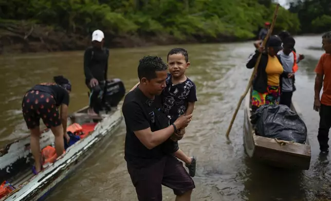 Brayan Quintero and his son Brian, from Venezuela, arrive by boat to Lajas Blancas, Panama, Thursday, Sept. 26, 2024, after walking across the Darien Gap in hopes of reaching the U.S. (AP Photo/Matias Delacroix)