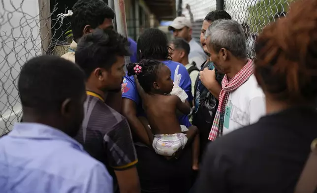 Dorcas Many carries her daughter at a camp for migrants who walked across the Darien Gap in hopes of reaching the U.S., in Lajas Blancas, Panama, Thursday, Sept. 26, 2024. (AP Photo/Matias Delacroix)