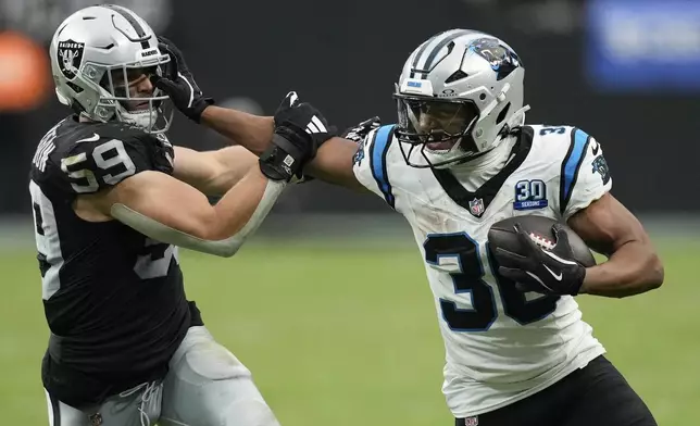 Carolina Panthers running back Chuba Hubbard runs around Las Vegas Raiders linebacker Luke Masterson during the second half of an NFL football game, Sunday, Sept. 22, 2024, in Las Vegas. (AP Photo/John Locher)