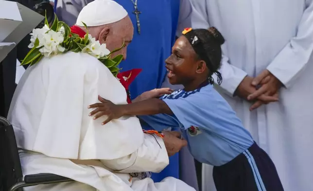 Pope Francis is hugged by a blind pupil of the Holy Trinity Humanistic School in Baro, near Vanimo, Papua New Guinea, Sunday, Sept. 8, 2024. Pope Francis celebrated the Catholic Church of the peripheries on Sunday as he traveled to the remote jungles of Papua New Guinea, bringing with him a ton of medicine and toys and a message of love overcoming violence for the people who live there.(AP Photo/Gregorio Borgia)