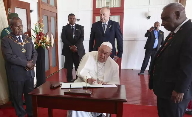 Pope Francis signs the book of honor as he meets with the Papua New Guinea's Governor General Sir Bob Dadae at the Government House in Port Moresby, Papua New Guinea, Saturday, Sept. 7, 2024. (Guglielmo Mangiapane/Pool Photo via AP)