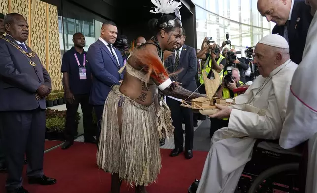 Pope Francis is presented with a wooden model of a traditional boat outside the APEC Haus in Port Moresby, Saturday, Sept. 7, 2024, as he arrives with Papua New Guinea's Governor General Bob Dadae, left. As a second leg of his 11-day trip to Asia and Oceania Pope Francis's visit to Papua New Guinea will take him to a remote part of the South Pacific island nation where Christianity is a recent addition to traditional spiritual beliefs developed over millennia. (AP Photo/Gregorio Borgia)