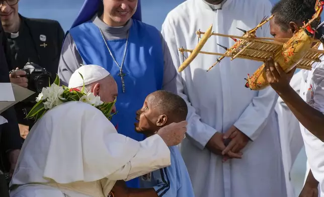 Pope Francis hugs a blind pupil of the Holy Trinity Humanistic School in Baro, near Vanimo, Papua New Guinea, Sunday, Sept. 8, 2024. Pope Francis celebrated the Catholic Church of the peripheries on Sunday as he traveled to the remote jungles of Papua New Guinea, bringing with him a ton of medicine and toys and a message of love overcoming violence for the people who live there.(AP Photo/Gregorio Borgia)