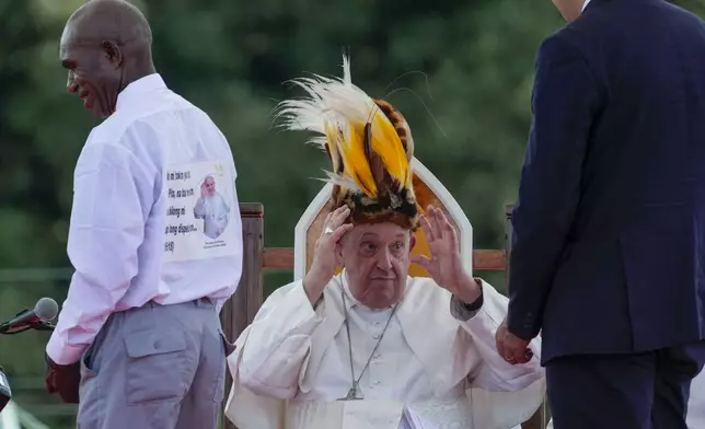 Pope Francis receives a traditional hat during a meeting with faithful in Vanimo, Papua New Guinea, Sunday, Sept. 8, 2024. Pope Francis celebrated the Catholic Church of the peripheries on Sunday as he traveled to the remote jungles of Papua New Guinea, bringing with him a ton of medicine and toys and a message of love overcoming violence for the people who live there.(AP Photo/Gregorio Borgia)