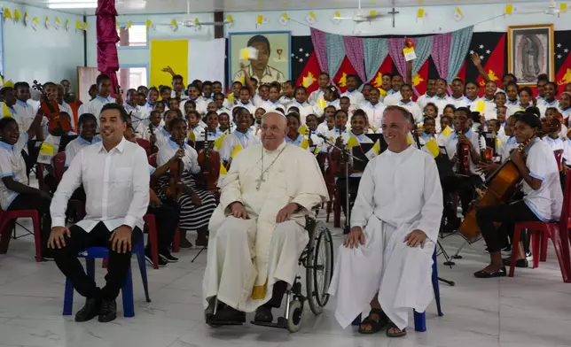 Pope Francis, center, poses for a photo in the School &amp; Queen of Paradise Hall at the Holy Trinity Humanistic School in Baro, near Vanimo, Papua New Guinea, Sunday, Sept. 8, 2024, where he attended a short concert by the school's student orchestra. Pope Francis celebrated the Catholic Church of the peripheries on Sunday as he traveled to the remote jungles of Papua New Guinea, bringing with him a ton of medicine and toys and a message of love overcoming violence for the people who live there.(AP Photo/Gregorio Borgia)