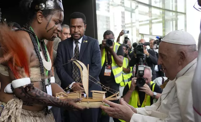 Pope Francis is presented with a wooden model of a traditional boat outside the APEC Haus in Port Moresby, Saturday, Sept. 7, 2024, as he arrives to meet with Papua New Guinea's political and religious authorities, the diplomatic corps, entrepreneurs, representatives of civil society and culture. As a second leg of his 11-day trip to Asia and Oceania Pope Francis's visit to Papua New Guinea will take him to a remote part of the South Pacific island nation where Christianity is a recent addition to traditional spiritual beliefs developed over millennia. (AP Photo/Gregorio Borgia)