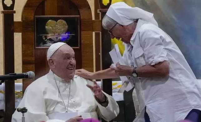 Pope Francis, laughs with Franciscan Sister of Divine Providence of Baldegg Lorena Jenal a meeting with the bishops of Papua New Guinea and Solomon Islands, priests, deacons, consecrated persons, seminarians and catechists in the Shrine of Mary Help of Christians. in Port Moresby, Saturday, Sept. 7, 2024. Pope Francis called Saturday for an end to tribal conflicts that have wracked Papua New Guinea for decades and appealed for equitable development of its natural resources during a visit that also surfaced the country's problem of violence against women. (AP Photo/Gregorio Borgia)