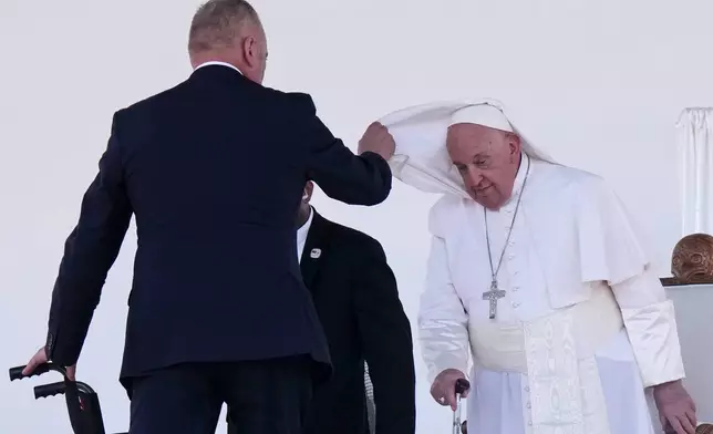 An aide assists Pope Francis with his cape after he gave an address during meeting with young people in the Sir John Guise Stadium in Port Moresby, Papua New Guinea, Monday, Sept. 9, 2024. (AP Photo/Mark Baker)