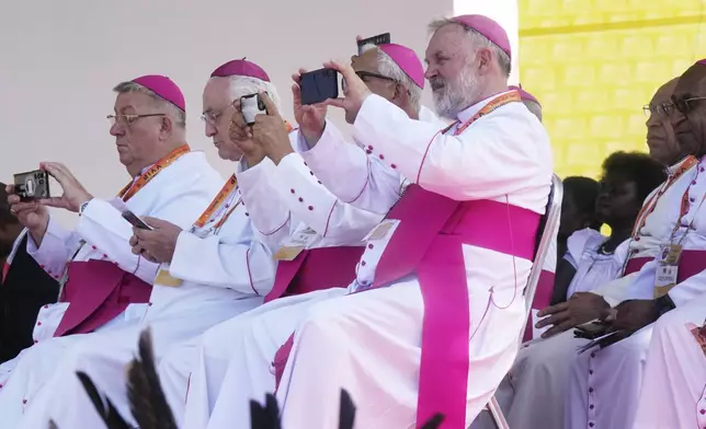 Clerics use their phones as Pope Francis gives an address during meeting with young people in the Sir John Guise Stadium in Port Moresby, Papua New Guinea, Monday, Sept. 9, 2024. (AP Photo/Mark Baker)