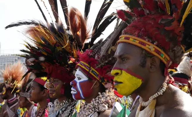 Men wear face paint a traditional headdress as they waits for Pope Francis to give an address during meeting with young people in the Sir John Guise Stadium in Port Moresby, Papua New Guinea, Monday, Sept. 9, 2024. (AP Photo/Mark Baker)