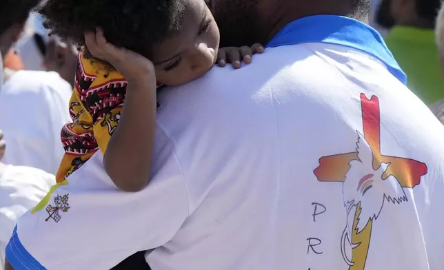 A man carries a child as Pope Francis holds a holly mass at Sir John Guise Stadium in Port Moresby, Papua New Guinea, Sunday, Sept. 8, 2024. (AP Photo/Mark Baker)