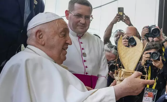 Pope Francis reacts after receiving a gift from a traditional dancer at APEC Haus in Port Moresby, Papua New Guinea, Saturday, Sept. 7, 2024. (AP Photo/Mark Baker)