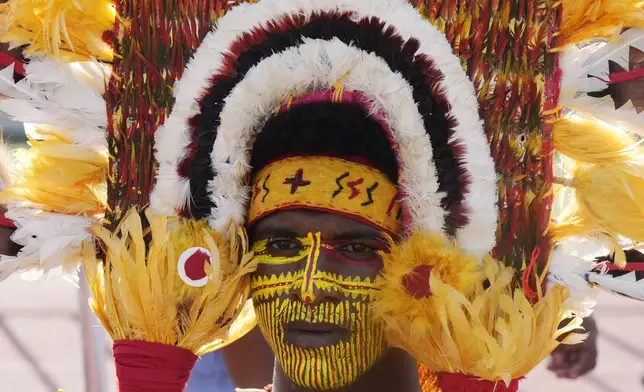 A man wears face paint a a traditional headdress as he waits for Pope Francis to give an address during meeting with young people in the Sir John Guise Stadium in Port Moresby, Papua New Guinea, Monday, Sept. 9, 2024. (AP Photo/Mark Baker)