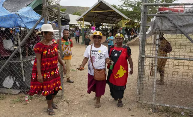 A woman, center, wears a shirt with a photo of Pope Francis at a market ahead of his visit to Port Moresby, Papua New Guinea, Friday, Sept. 6, 2024. (AP Photo/Mark Baker)